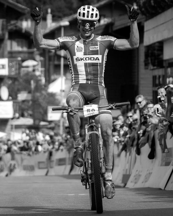 Kristián Hynek, sports director of Sideways Cycling, crossing a finish line with his arms raised
